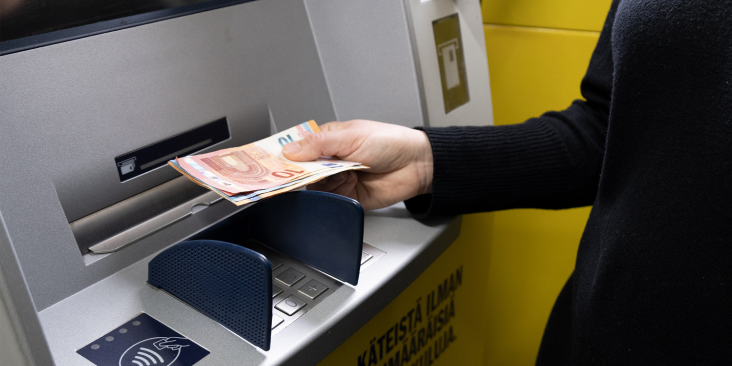 Henkilö nostamasta käteistä automaatilta.